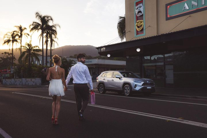 Toyota RAV4 on a palm lined street at dusk, Shanti Griffin crossing the road